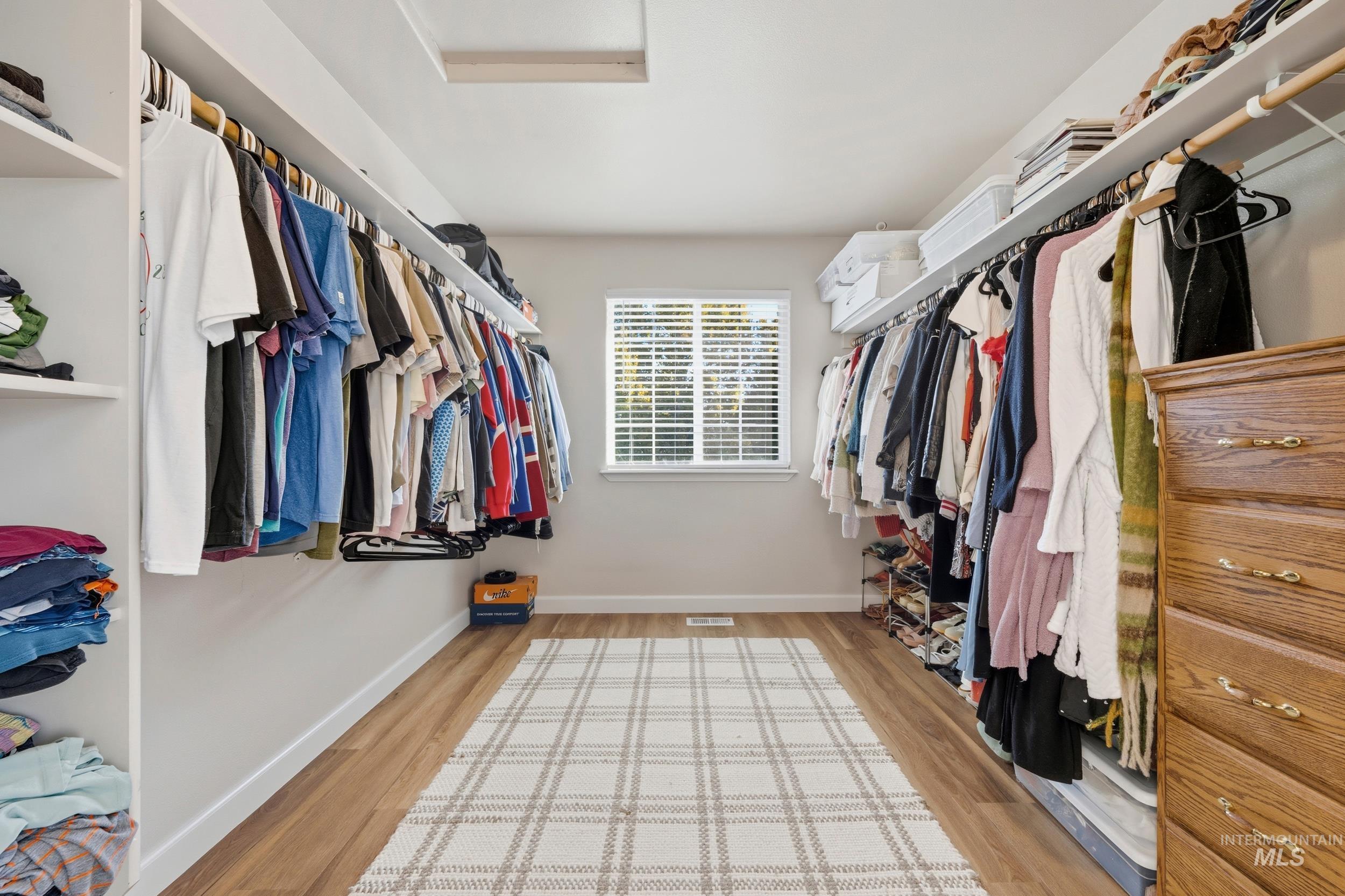 Spacious closet featuring light wood finished floors and attic access