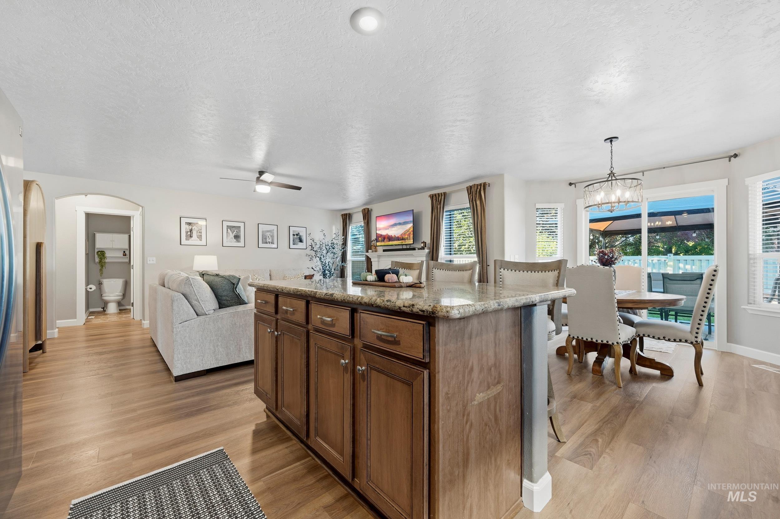 Kitchen featuring a breakfast bar, decorative light fixtures, a textured ceiling, light stone counters, and a kitchen island