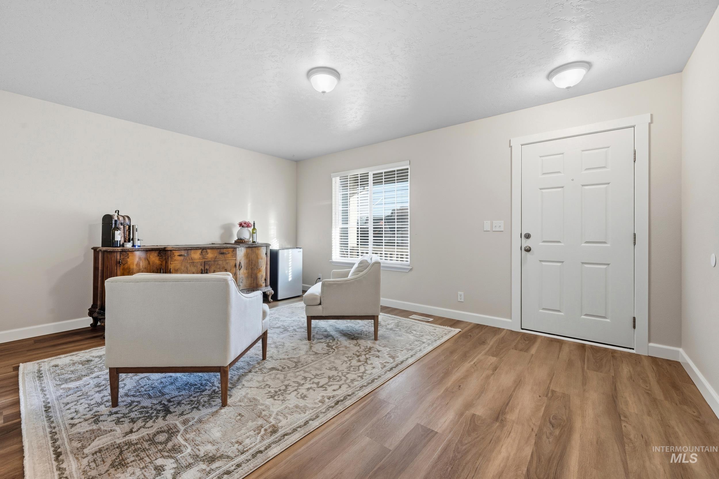 Sitting room with a textured ceiling and wood finished floors