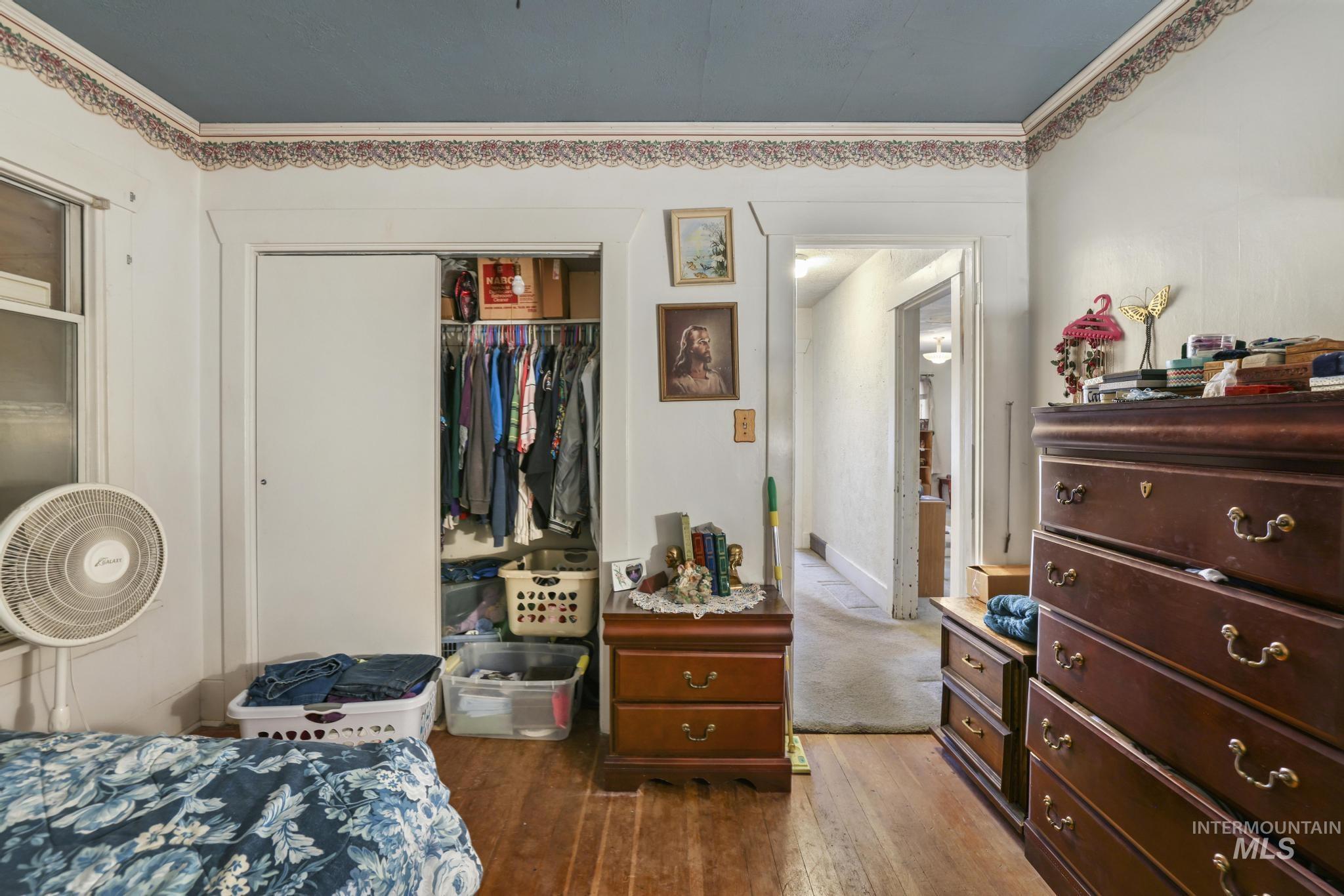 Bedroom with dark wood-type flooring, a closet, and ornamental molding