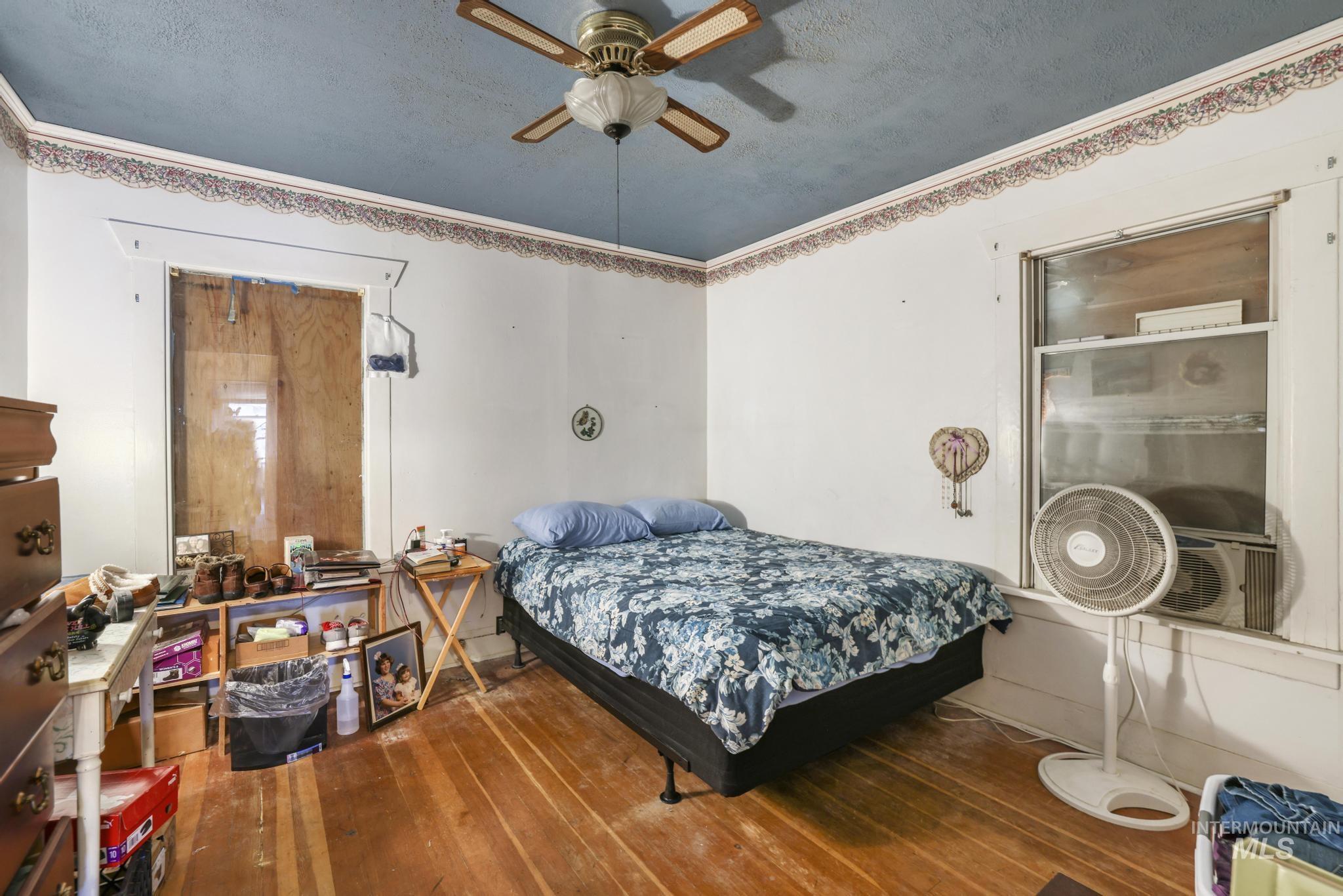 Bedroom featuring hardwood / wood-style flooring, a textured ceiling, a ceiling fan, and ornamental molding