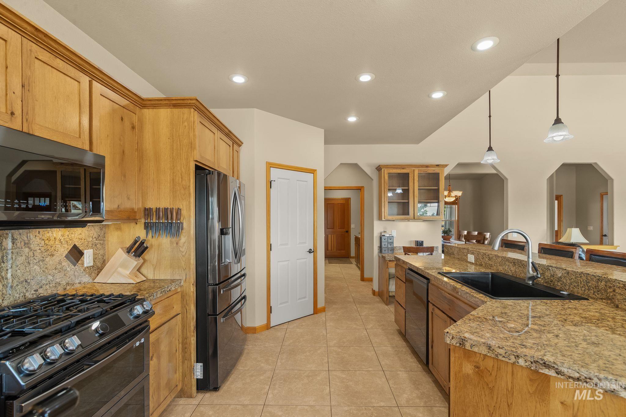 Open-concept kitchen featuring wood cabinetry, granite-finish countertops, and tile flooring