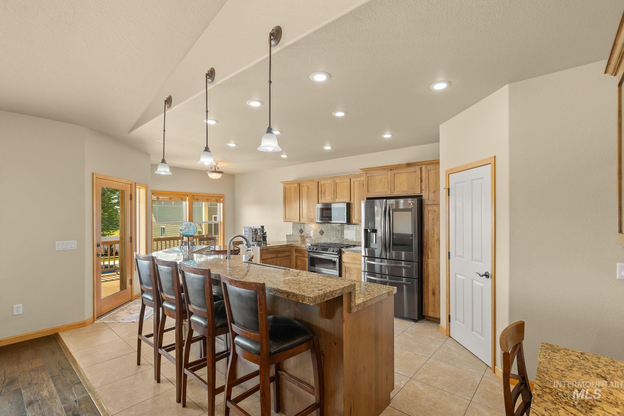 Kitchen featuring a large central island with seating, ample wood cabinetry, stainless steel appliances, and recessed lighting