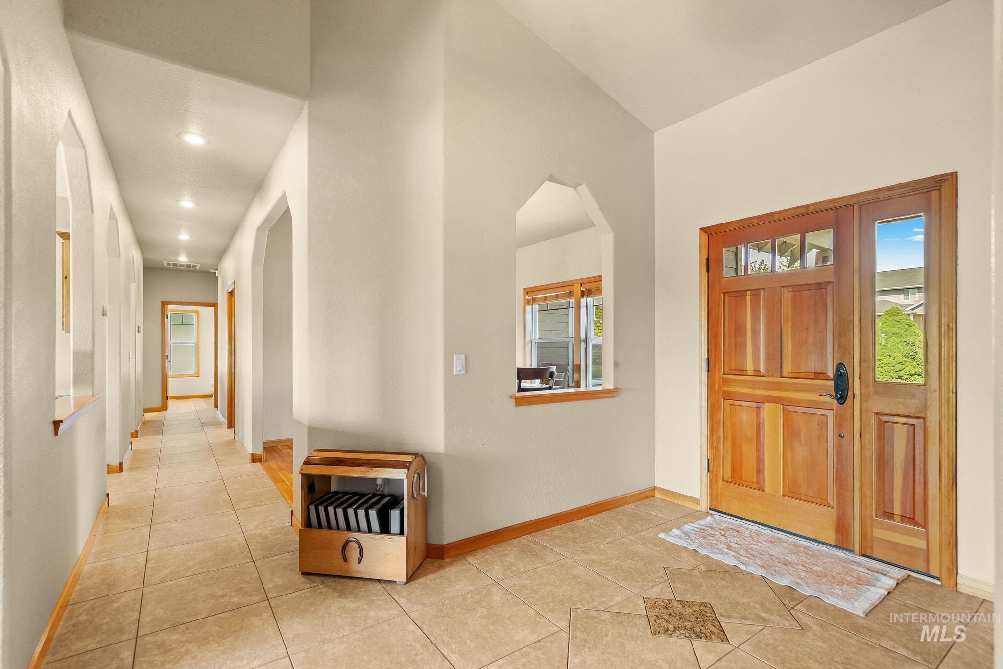 Entry foyer featuring a craftsman-style wooden door with a sidelight, and a tiled floor with an accent inlay