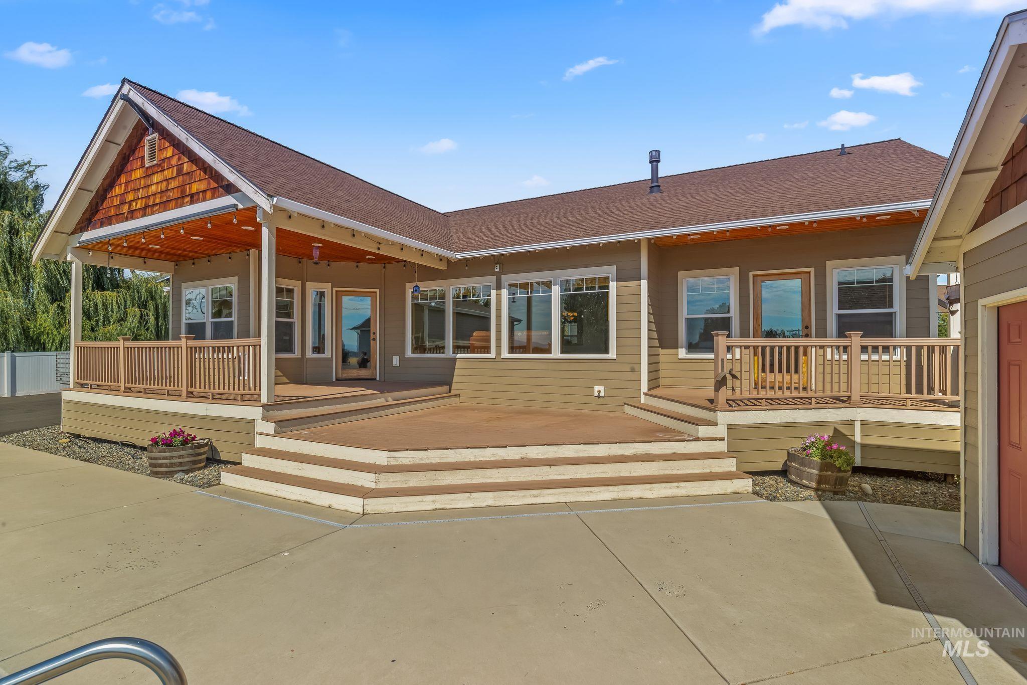Expansive multi-level wood deck featuring a covered patio with wood-plank ceiling, wood railing, and multiple windowed entry points