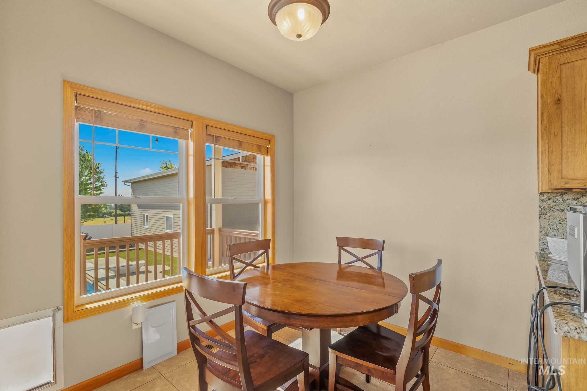 Dining area featuring tile flooring, neutral wall tones, and a pair of windows with wood-finish trim