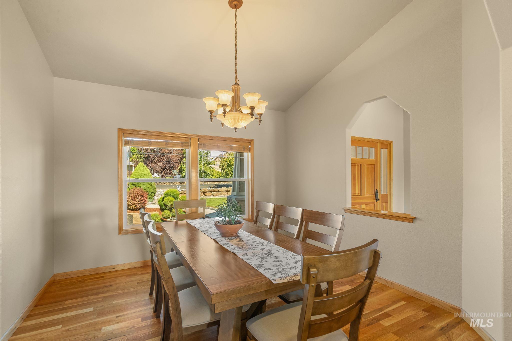 Vaulted ceiling dining area featuring wood-finish flooring and a multi-pane window with wood trim