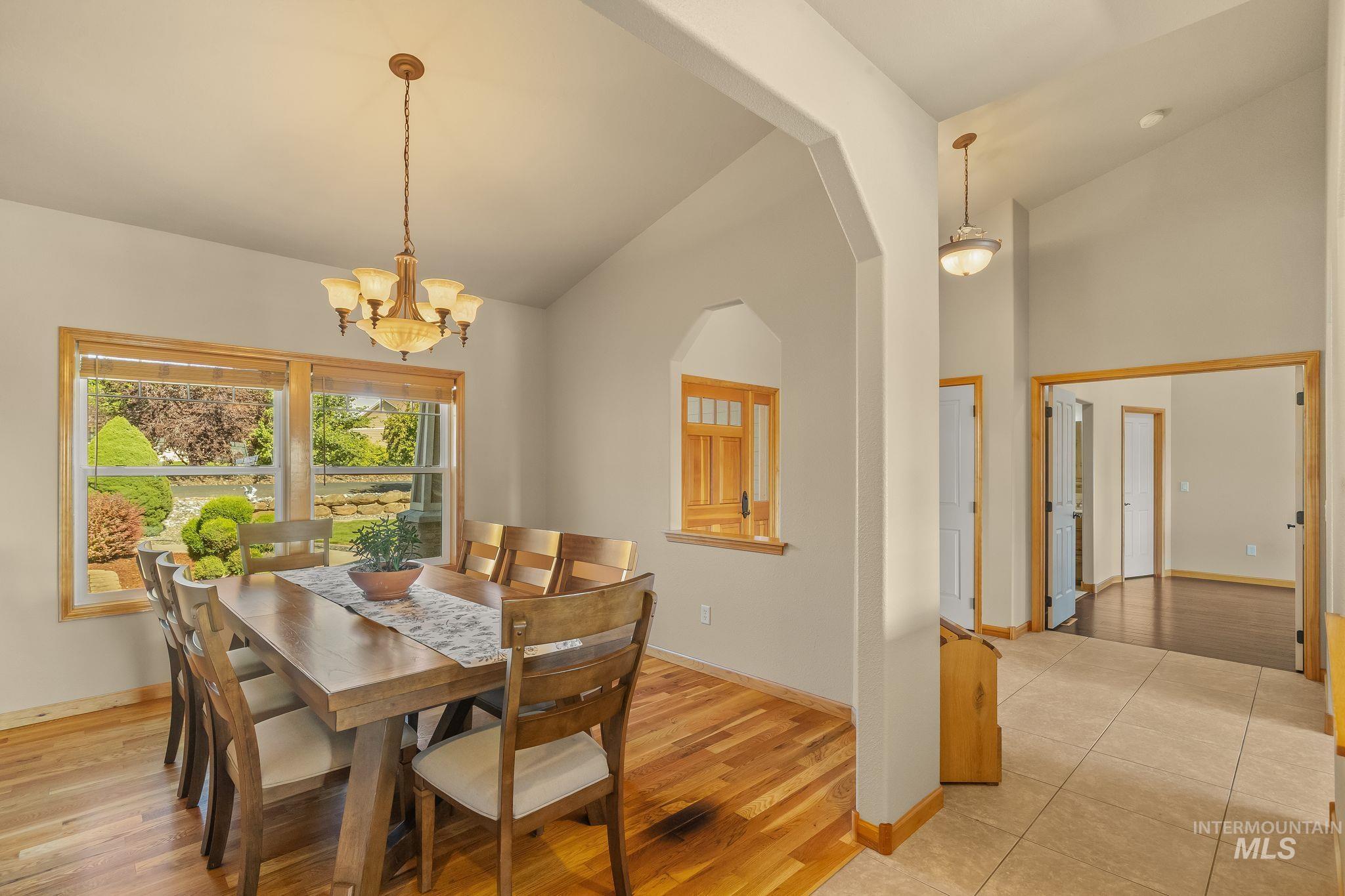 Dining area featuring high vaulted ceilings, light wood-finish flooring, and a chandelier