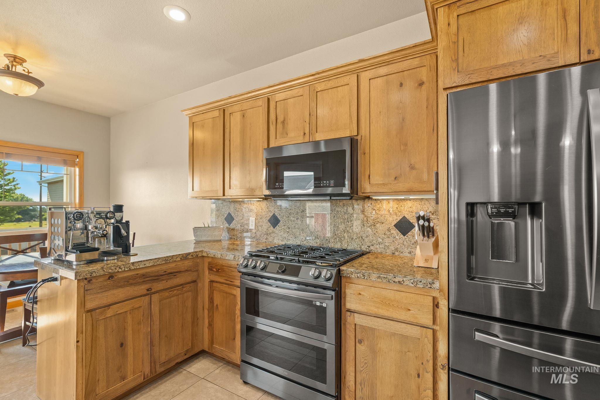 Kitchen featuring light wood cabinetry, granite countertops, and a full suite of stainless steel appliances