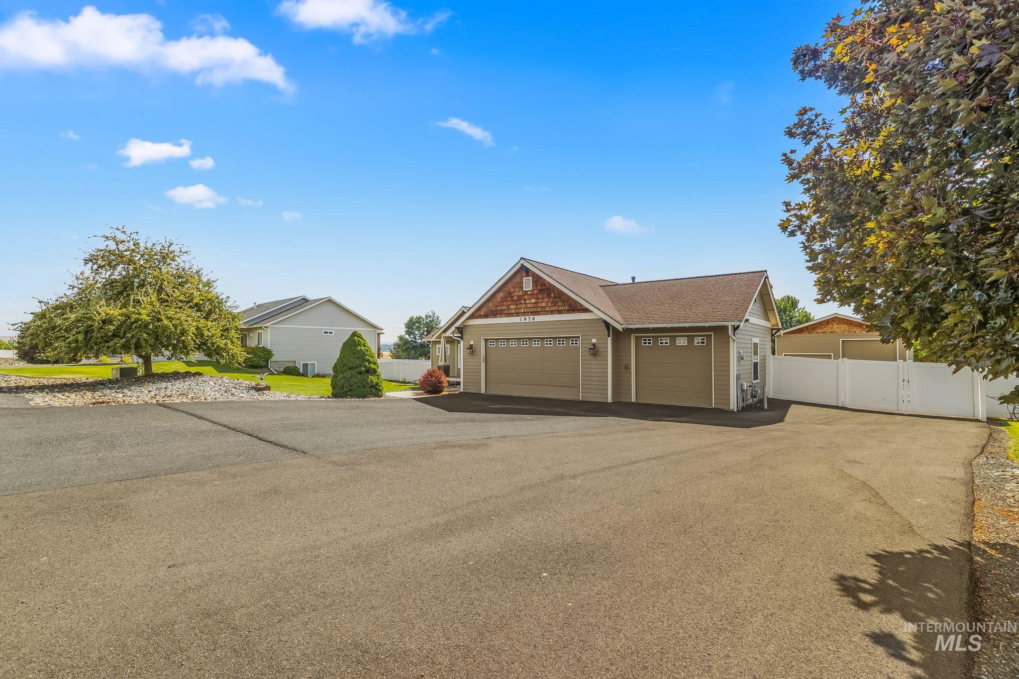 Ranch-style exterior with a paved driveway, attached garage, and a fenced side yard