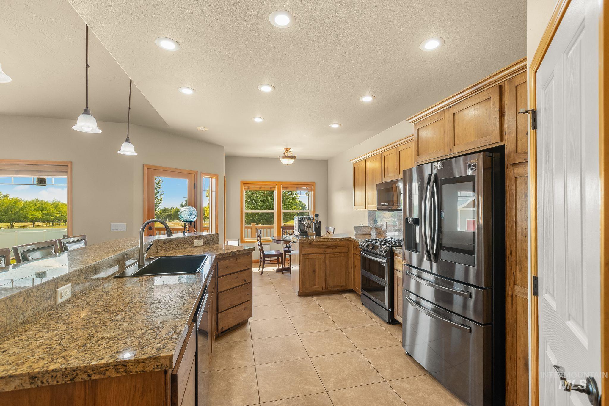 Kitchen featuring granite countertops, wood cabinetry, stainless steel appliances, and tile flooring
