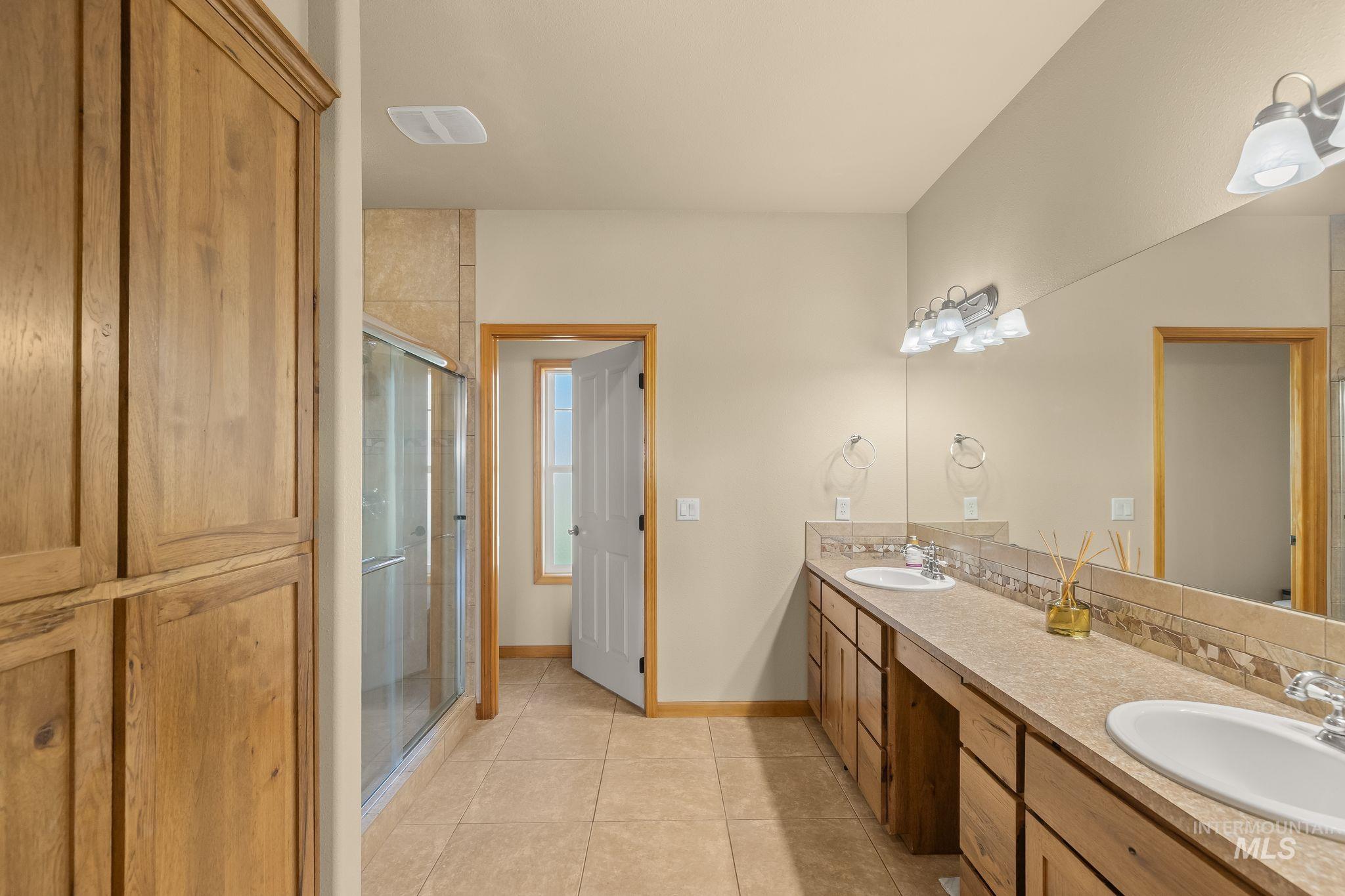 Bathroom featuring a dual vanity with integrated sinks, a full-width mirror, and a tiled backsplash