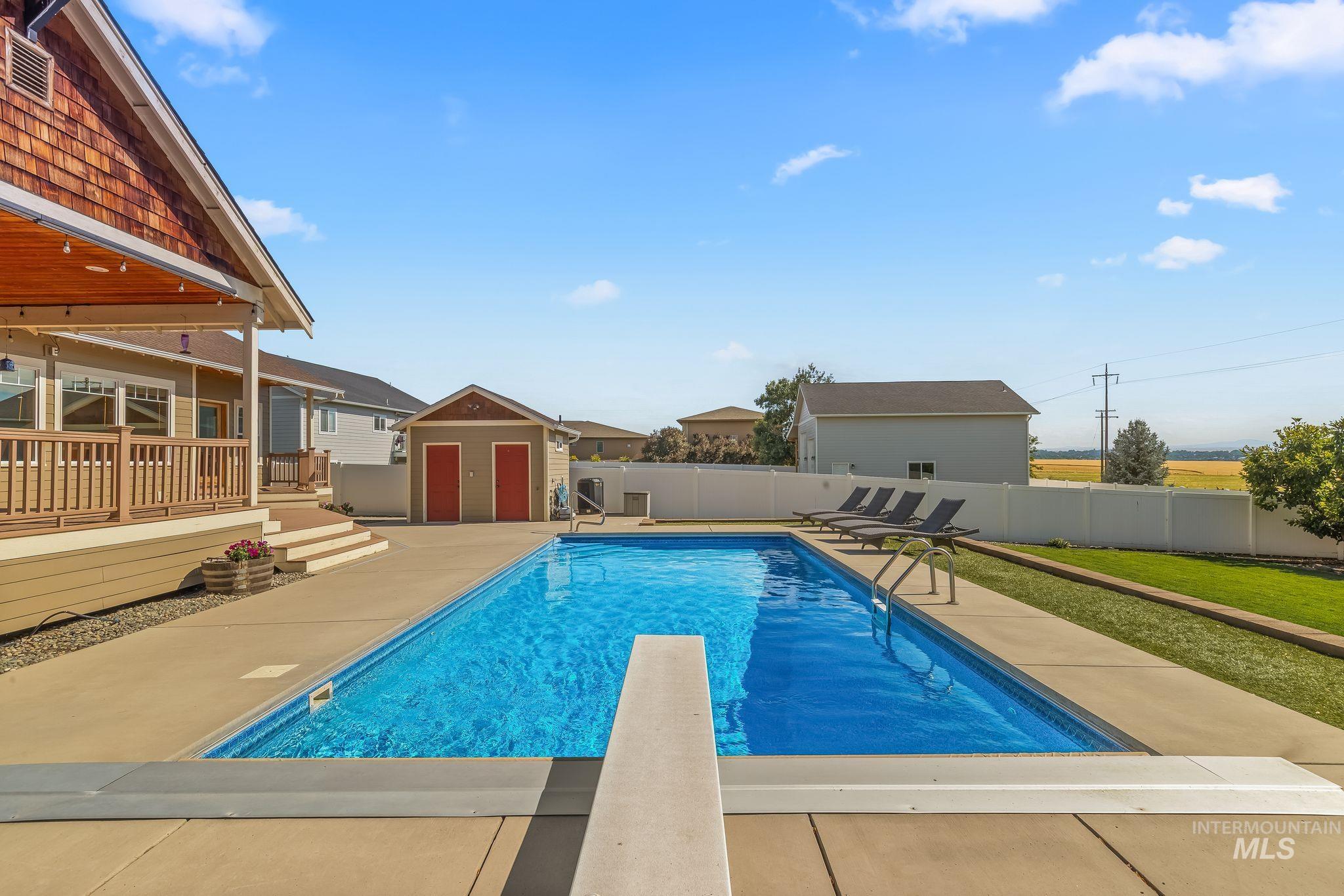 Rectangular inground pool featuring a diving board and concrete surround