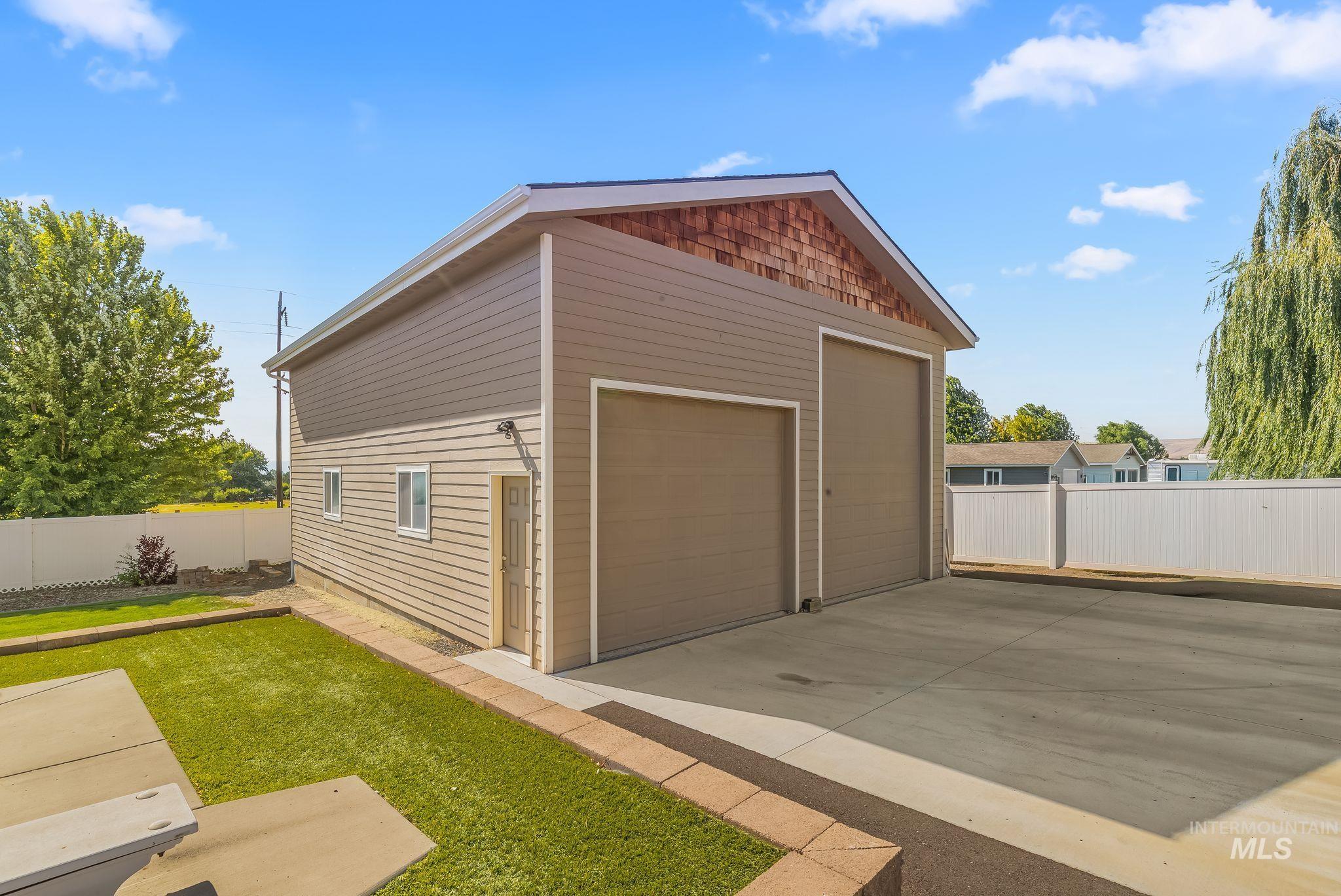 Two-story auxiliary building featuring dual garage doors, a pedestrian entry, and horizontal siding with an upper shingle accent
