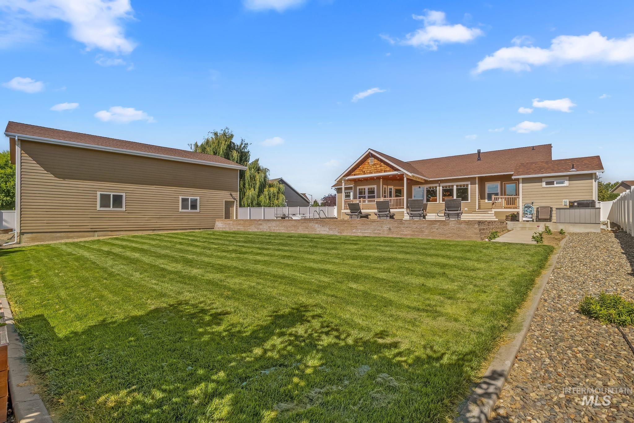 Expansive green lawn with a separate outbuilding and a main residence featuring a covered patio