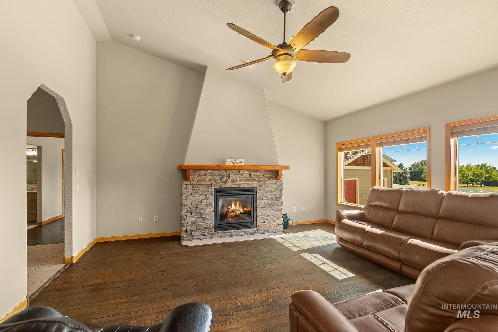 Vaulted ceiling living space featuring a stone-faced fireplace with a wood mantel
