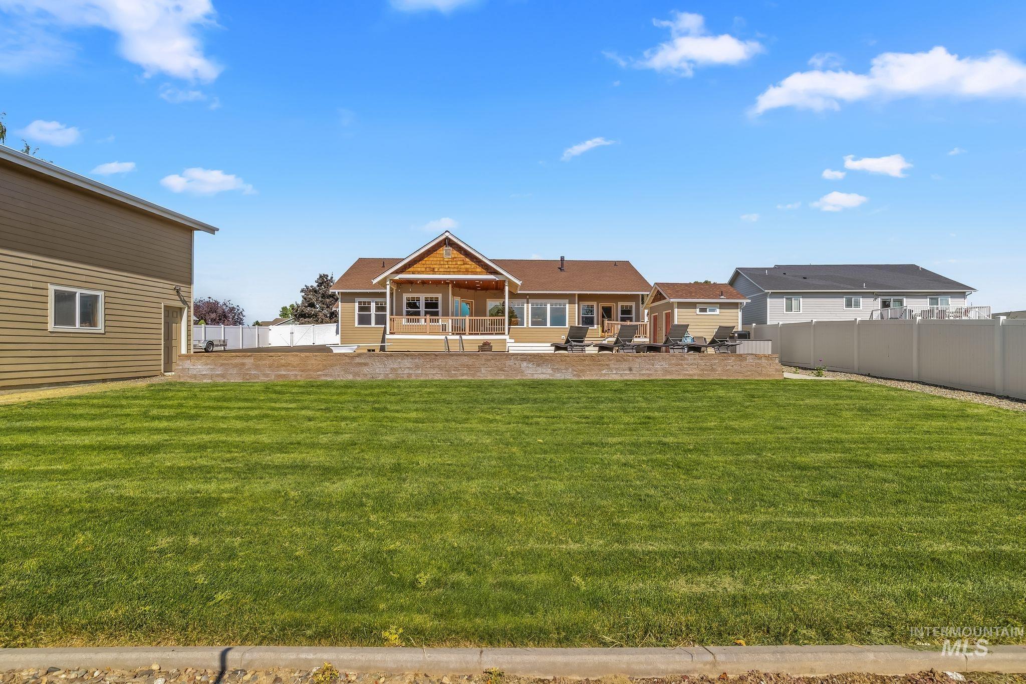 Expansive green lawn with a retaining wall leading to a rear patio