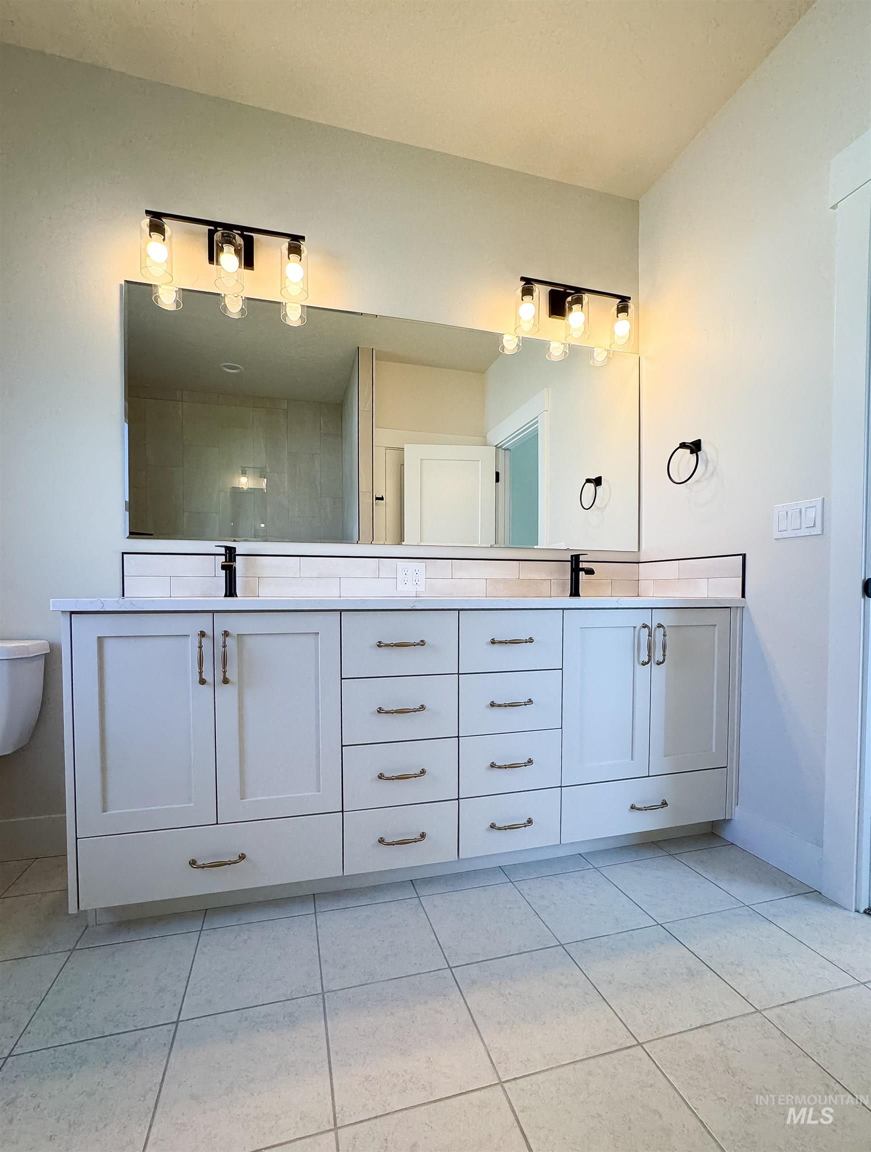 Bathroom with double vanity and tile patterned flooring