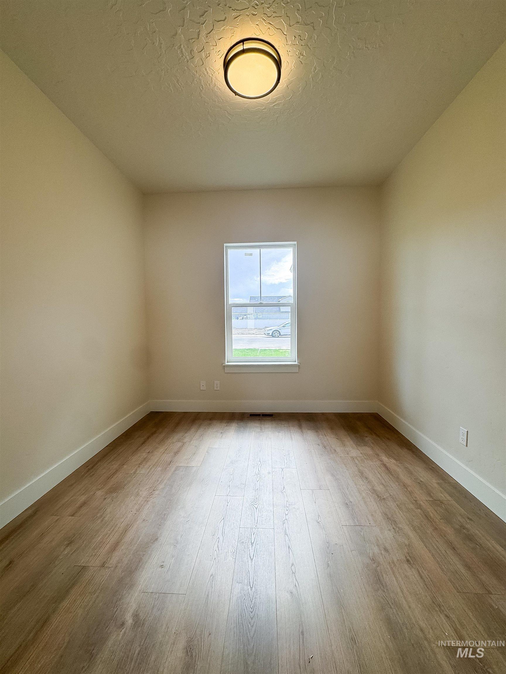 Empty room with a textured ceiling and wood finished floors