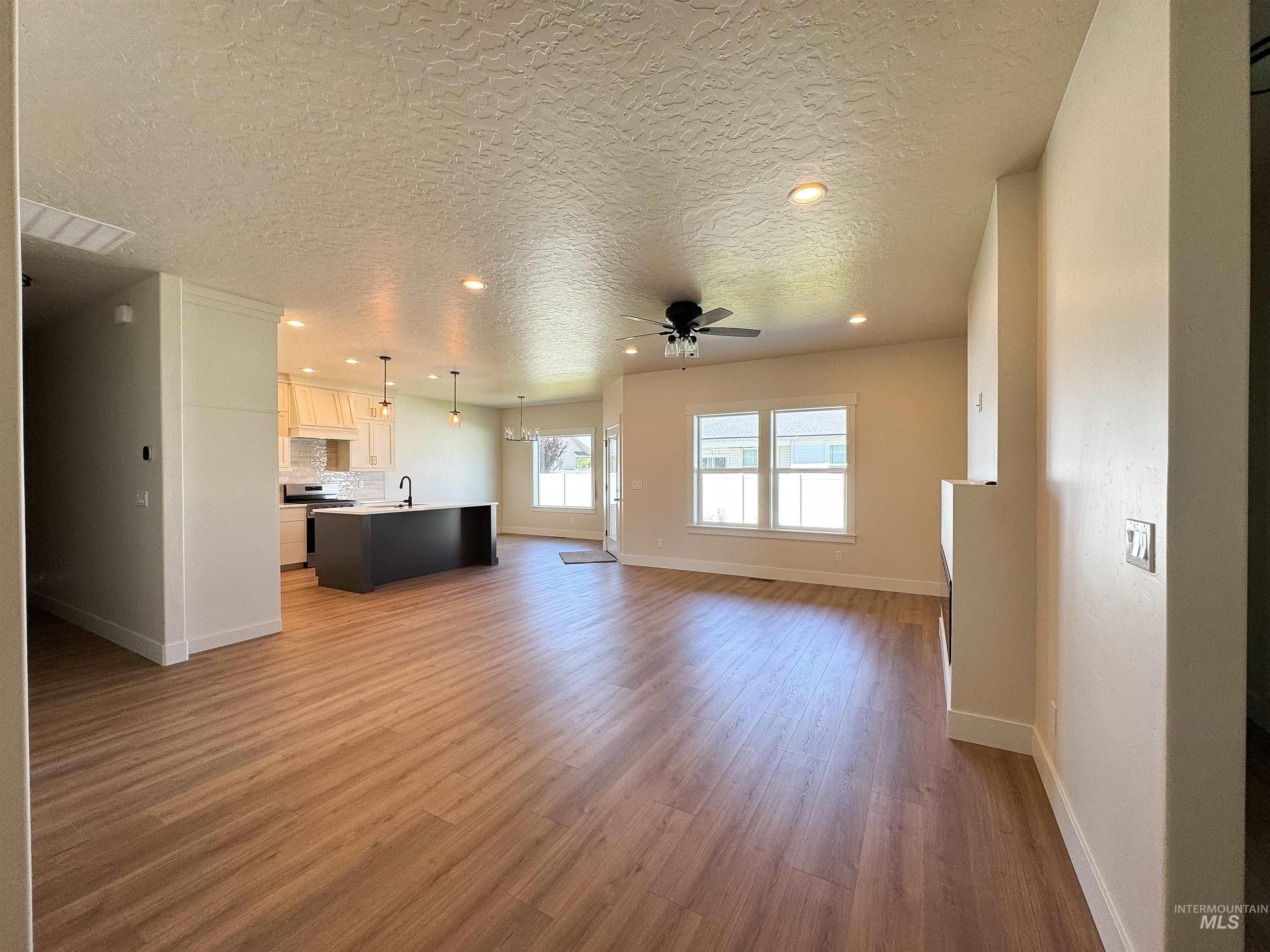 Unfurnished living room with ceiling fan, light wood finished floors, a textured ceiling, and recessed lighting