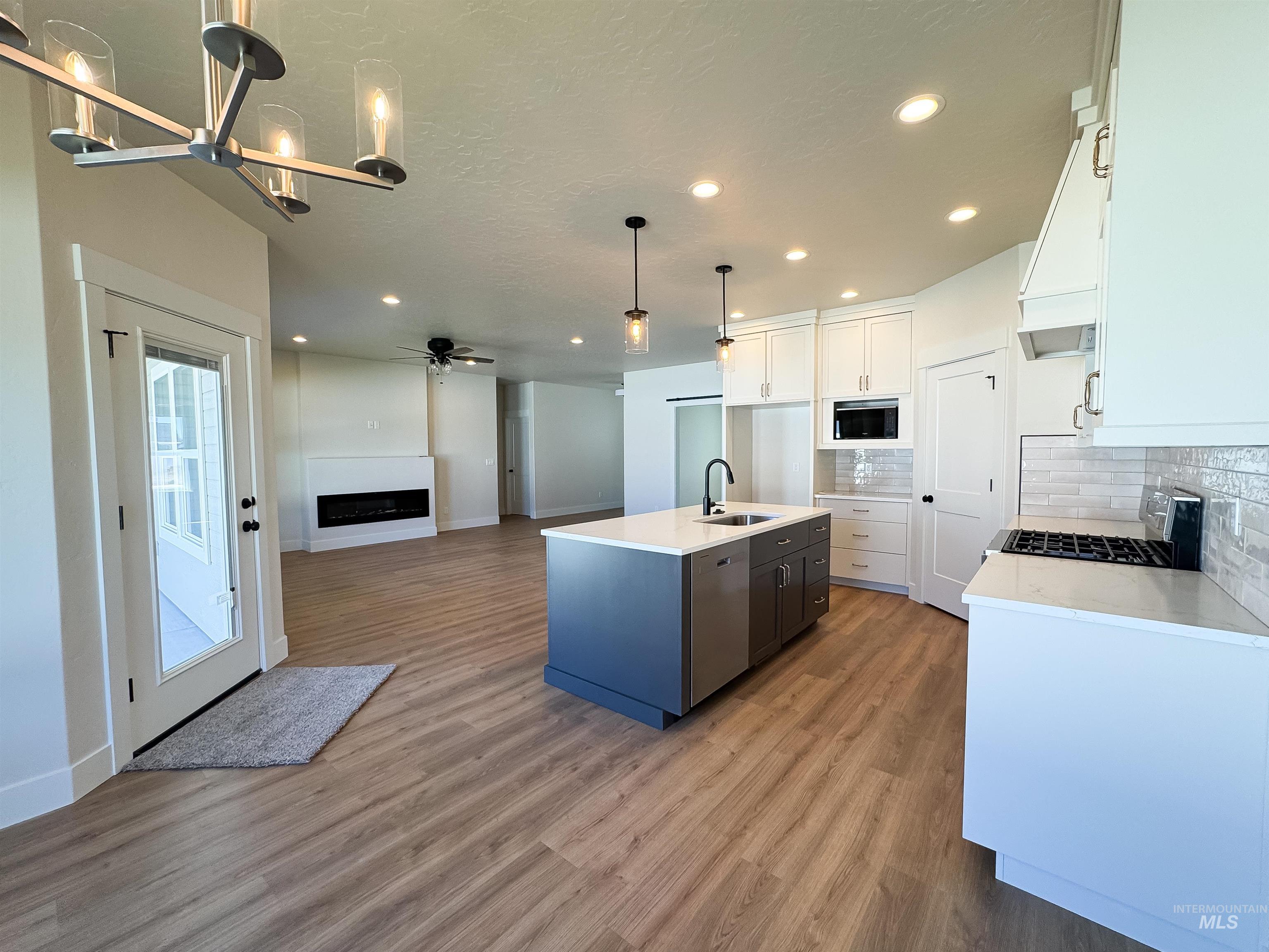 Kitchen featuring a fireplace, decorative backsplash, light wood-style floors, white cabinets, and recessed lighting