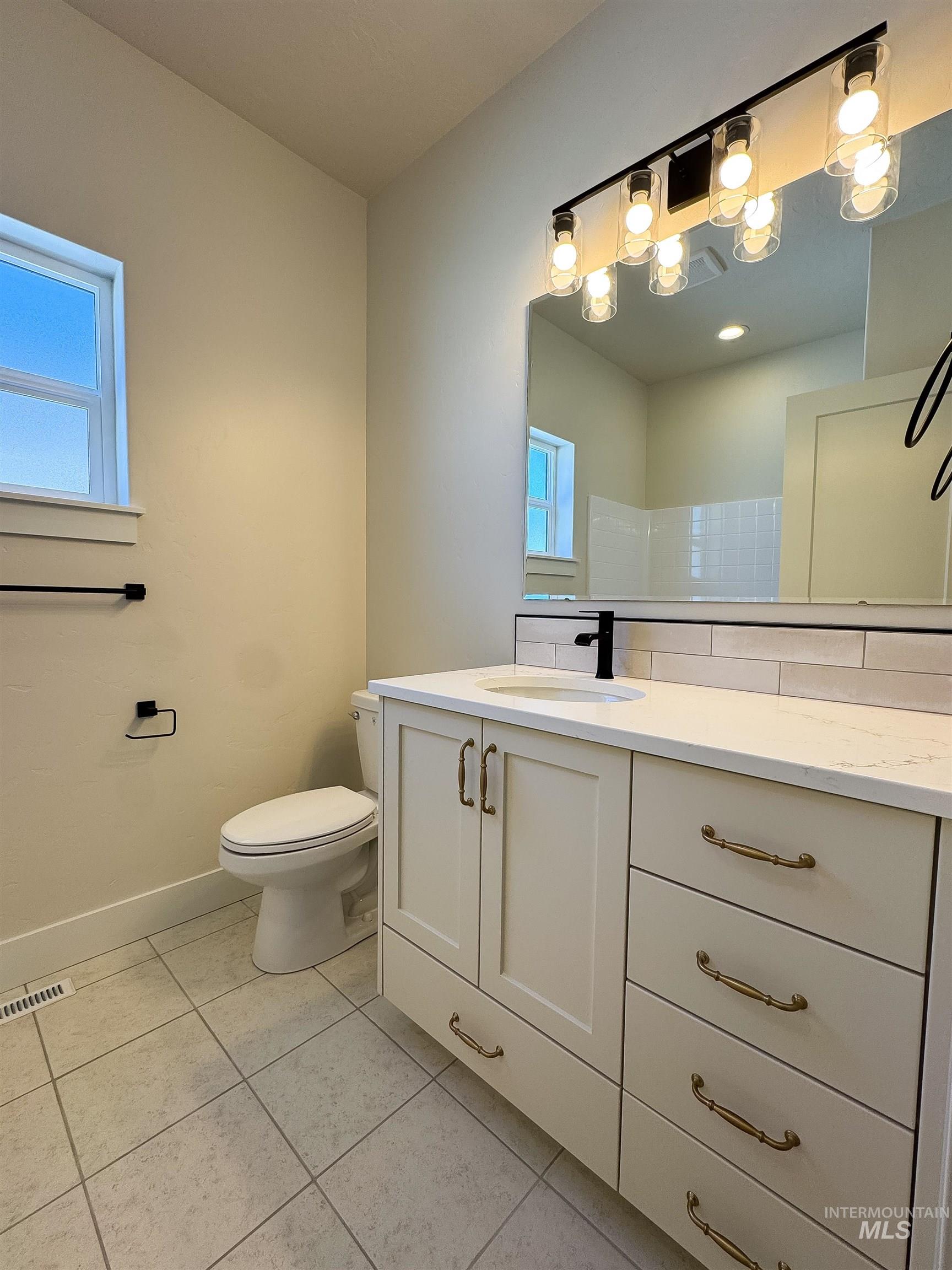 Bathroom with vanity, healthy amount of natural light, and tile patterned floors