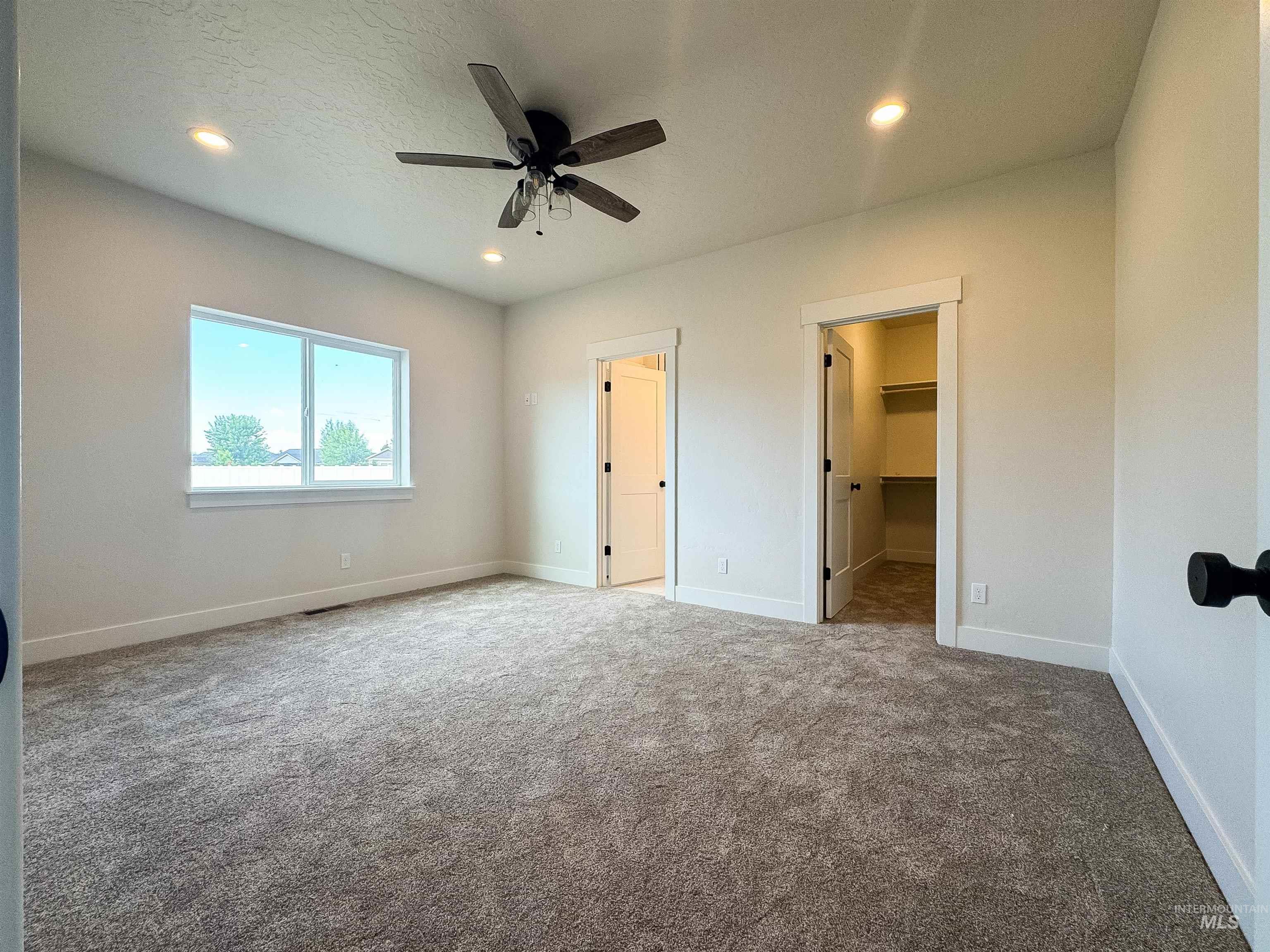 Unfurnished bedroom with carpet, recessed lighting, a walk in closet, and ceiling fan