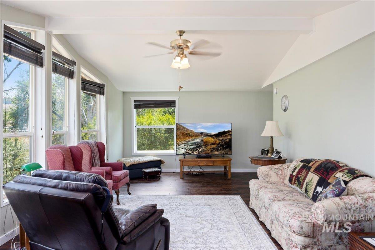 Living room featuring a ceiling fan and dark wood-style flooring