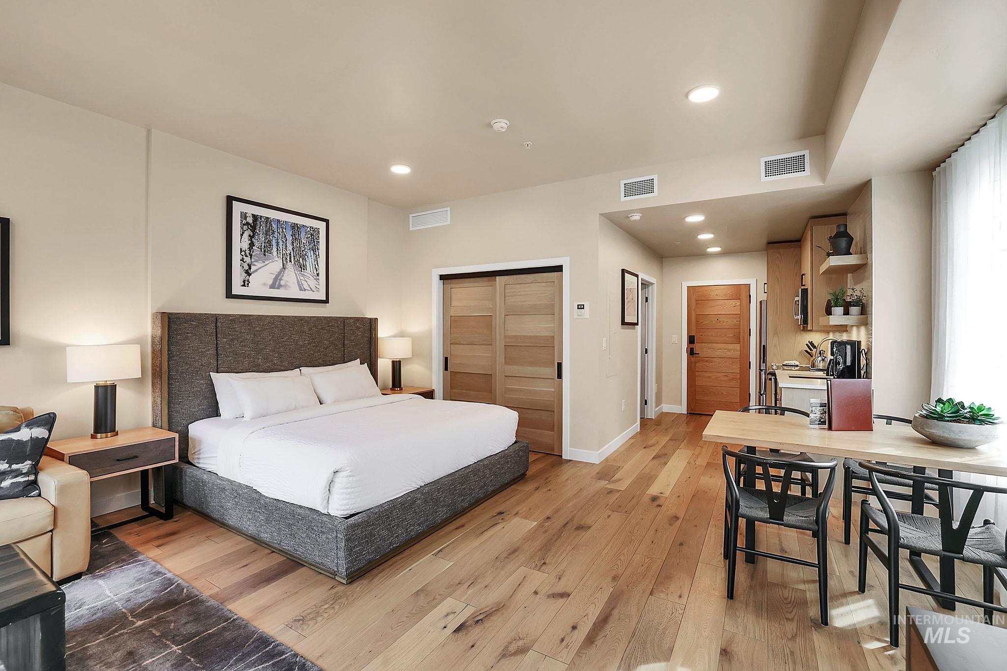 Bedroom with light wood finished floors, recessed lighting, and a closet
