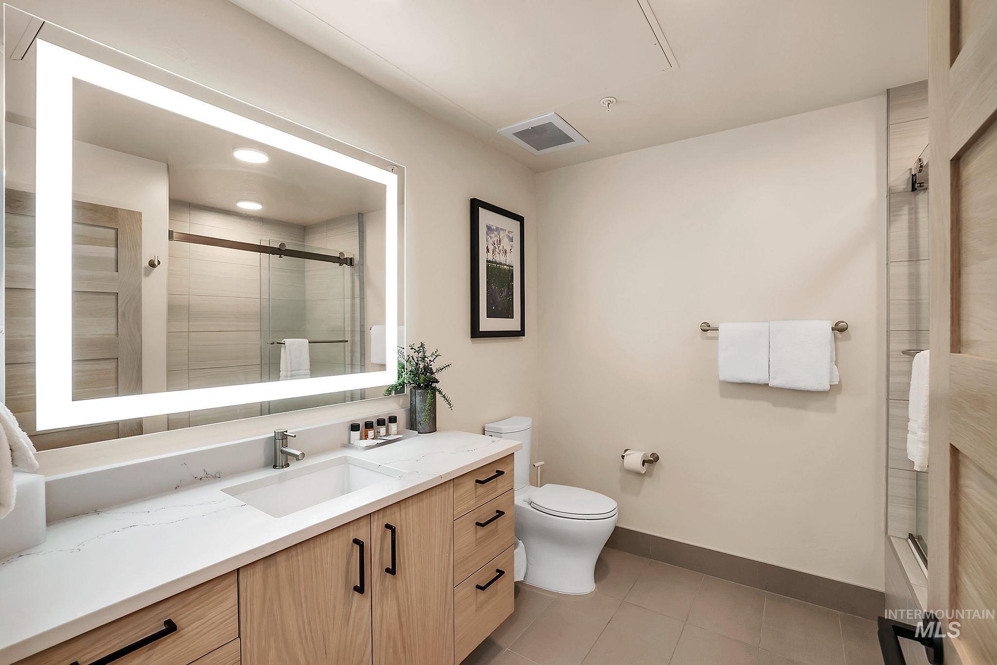 Full bathroom featuring vanity, light tile patterned floors, and a stall shower