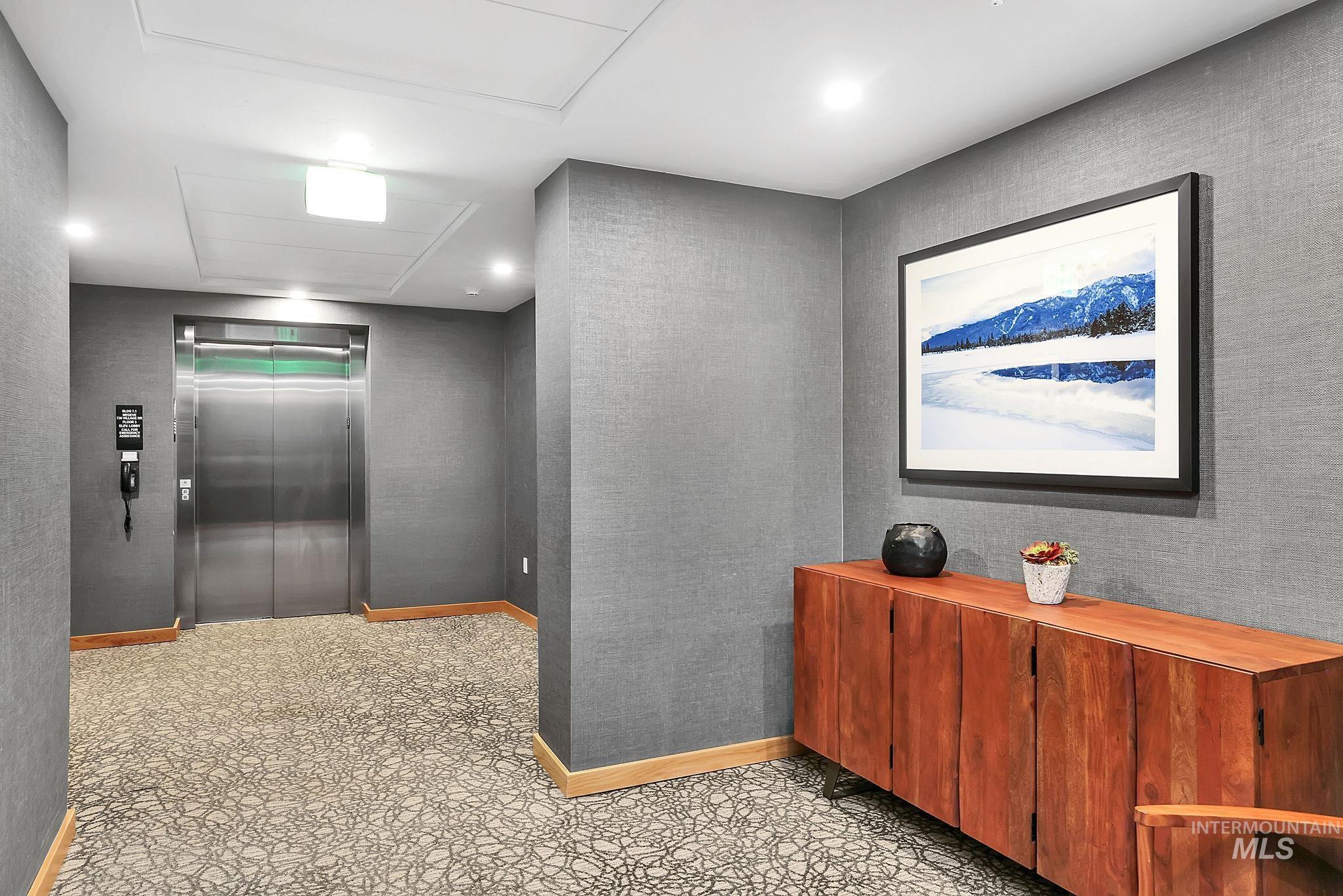 Corridor featuring elevator and baseboards