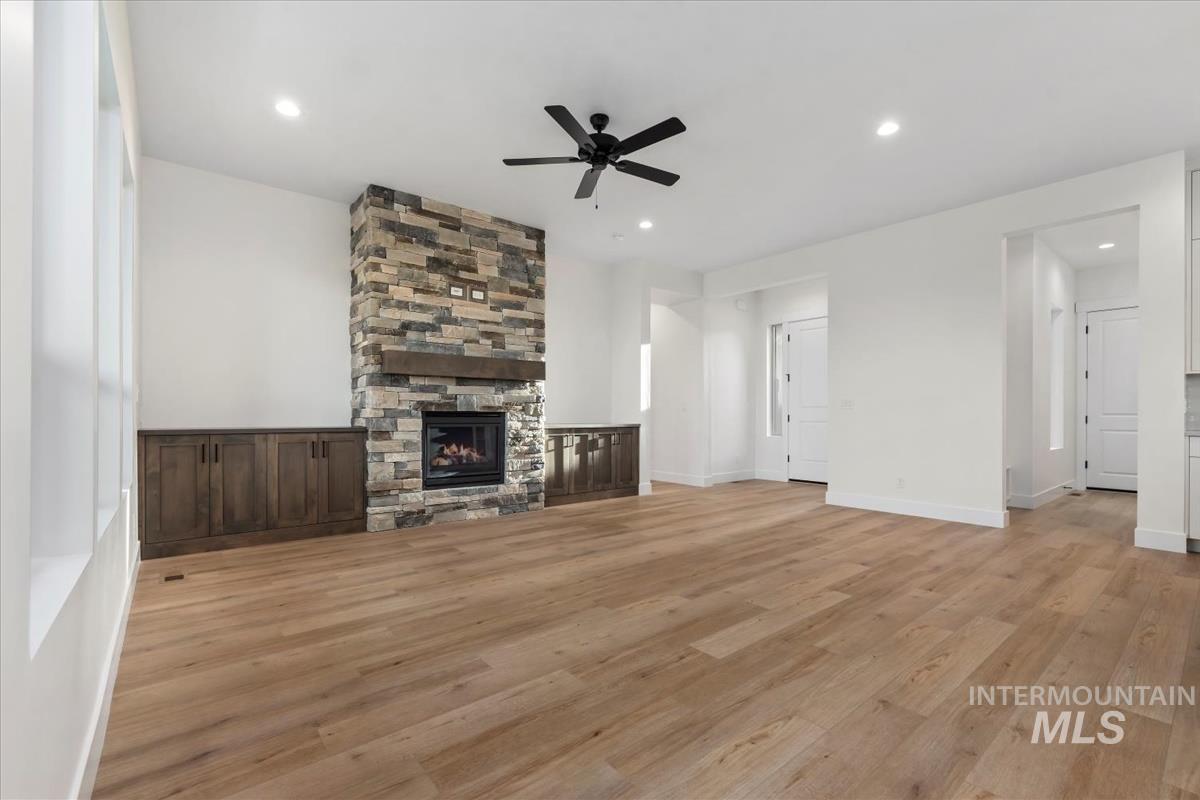 Unfurnished living room featuring light wood-style floors, recessed lighting, a fireplace, and a ceiling fan