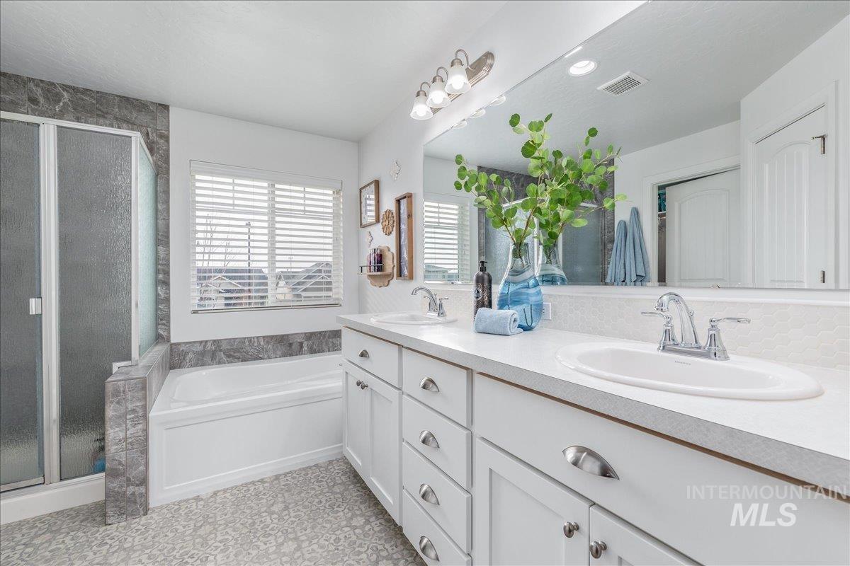 Full bath with double vanity, a stall shower, a garden tub, and recessed lighting