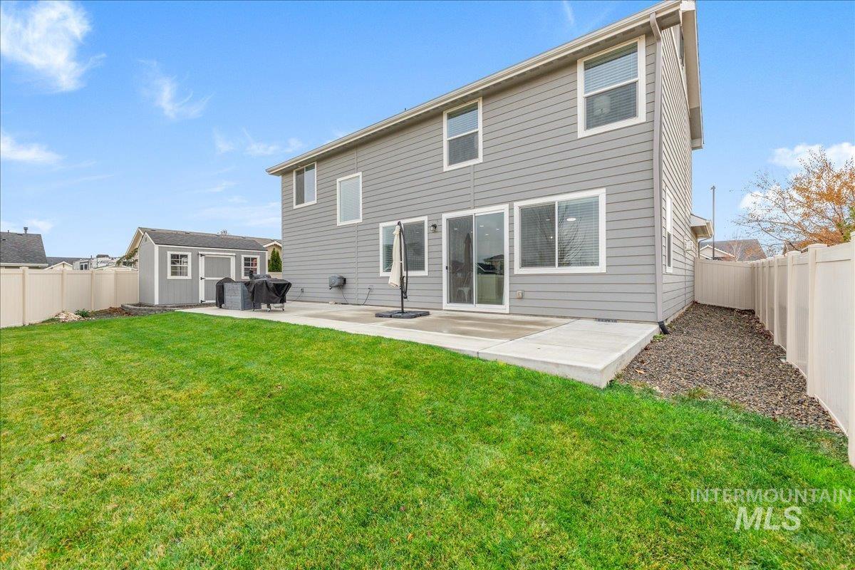 Rear view of property featuring a fenced backyard, a patio area, and a storage shed