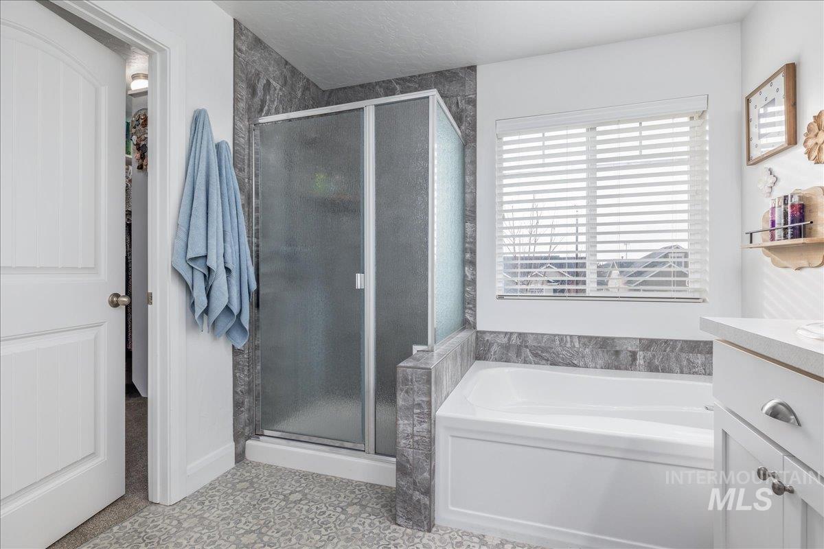 Bathroom featuring vanity, a garden tub, and a stall shower