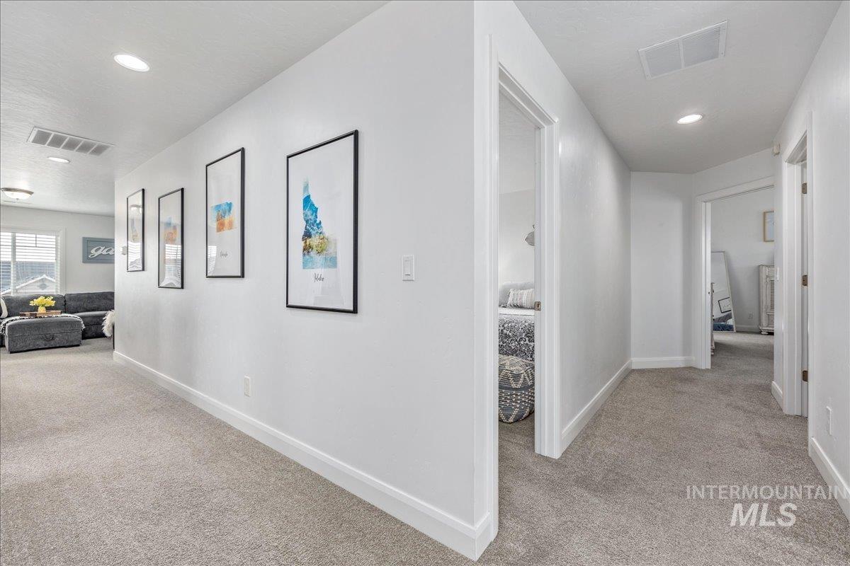 Corridor with light colored carpet and recessed lighting