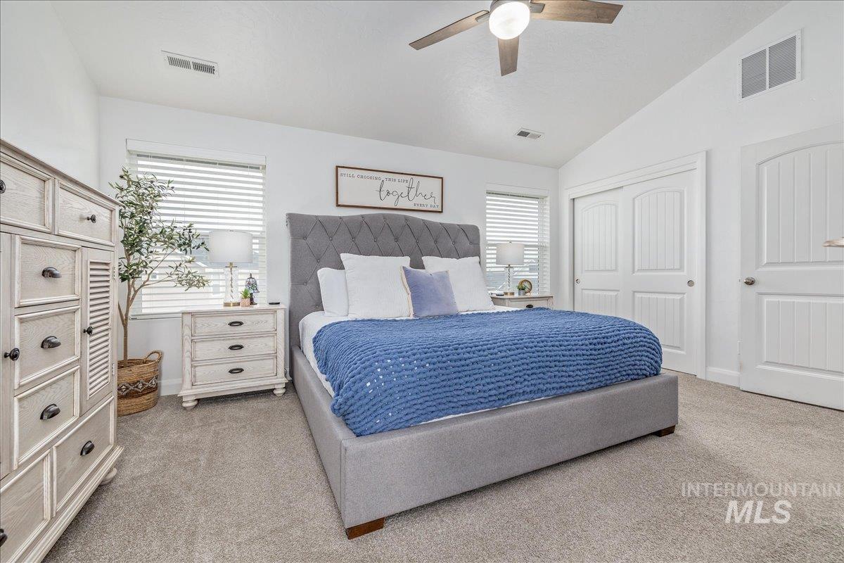 Bedroom featuring vaulted ceiling, light colored carpet, ceiling fan, and a closet
