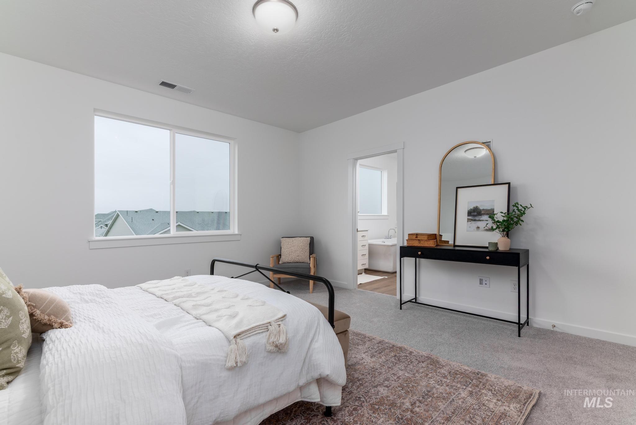 Bedroom featuring carpet flooring, multiple windows, and ensuite bathroom