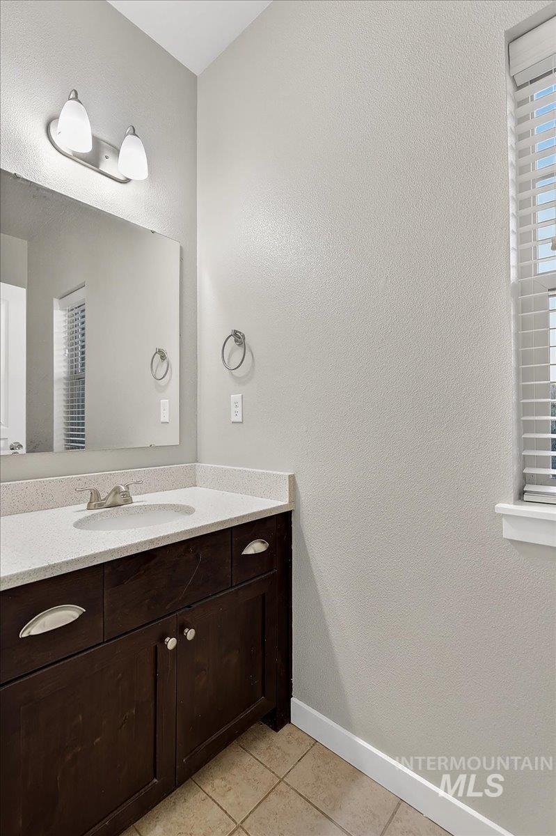 Bathroom vanity featuring a light-toned countertop, undermount sink, and dark wood-finish cabinetry with silver-tone hardware