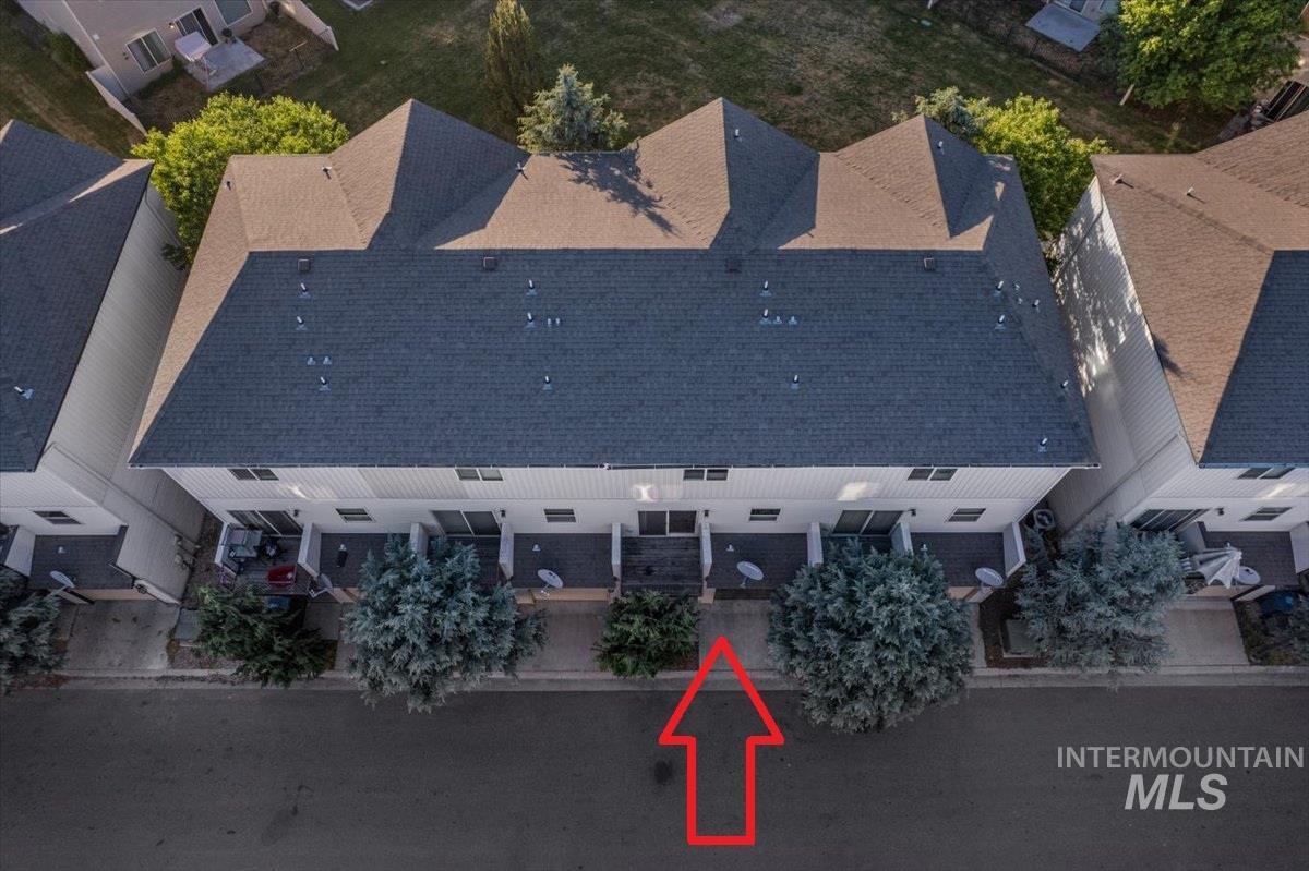 Townhome exterior featuring multiple private patios, mature landscaping, and a shingle roof