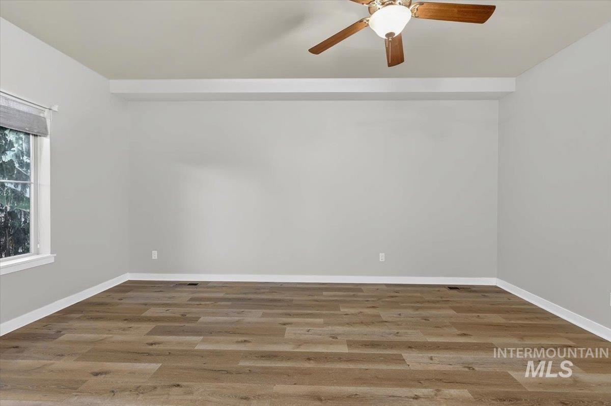 Spacious room featuring light gray walls, wood-finish flooring, and white trim