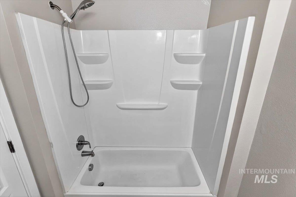 White tub and shower combination with integrated shelving