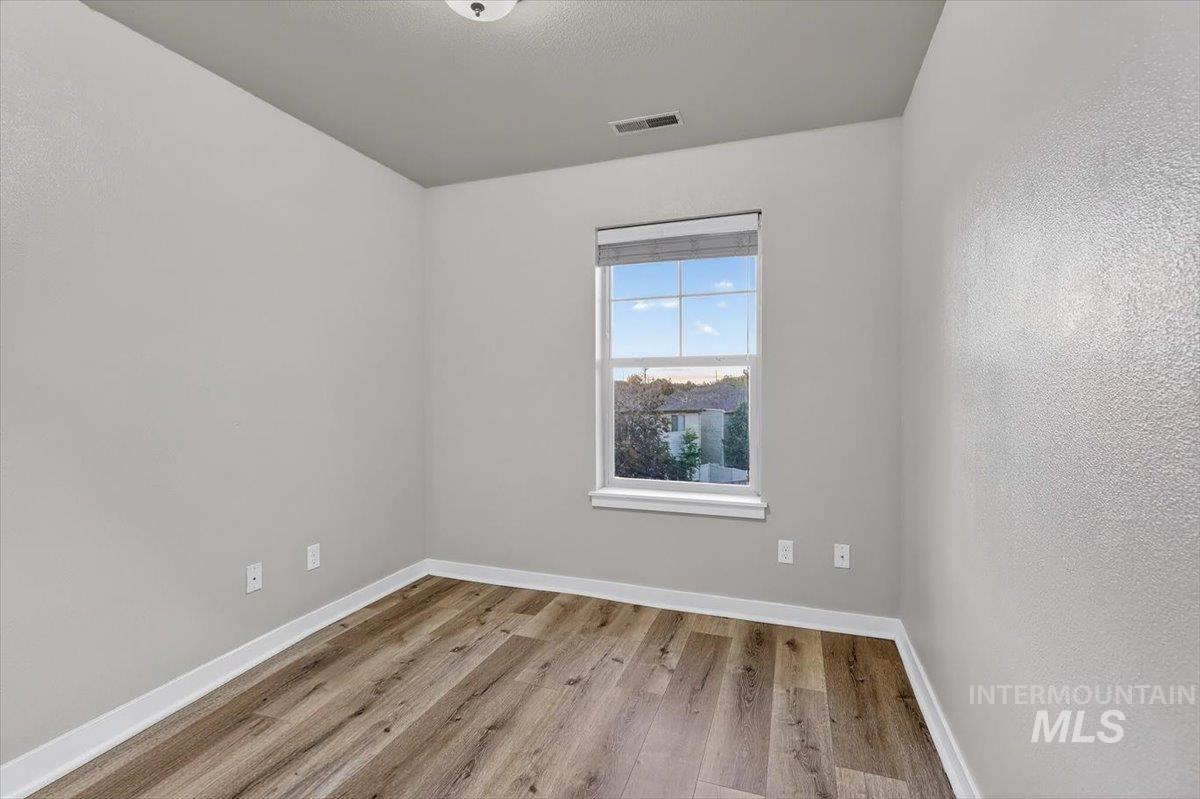 Single window featuring a privacy blind, wood-finish flooring, white baseboards, and a neutral wall color