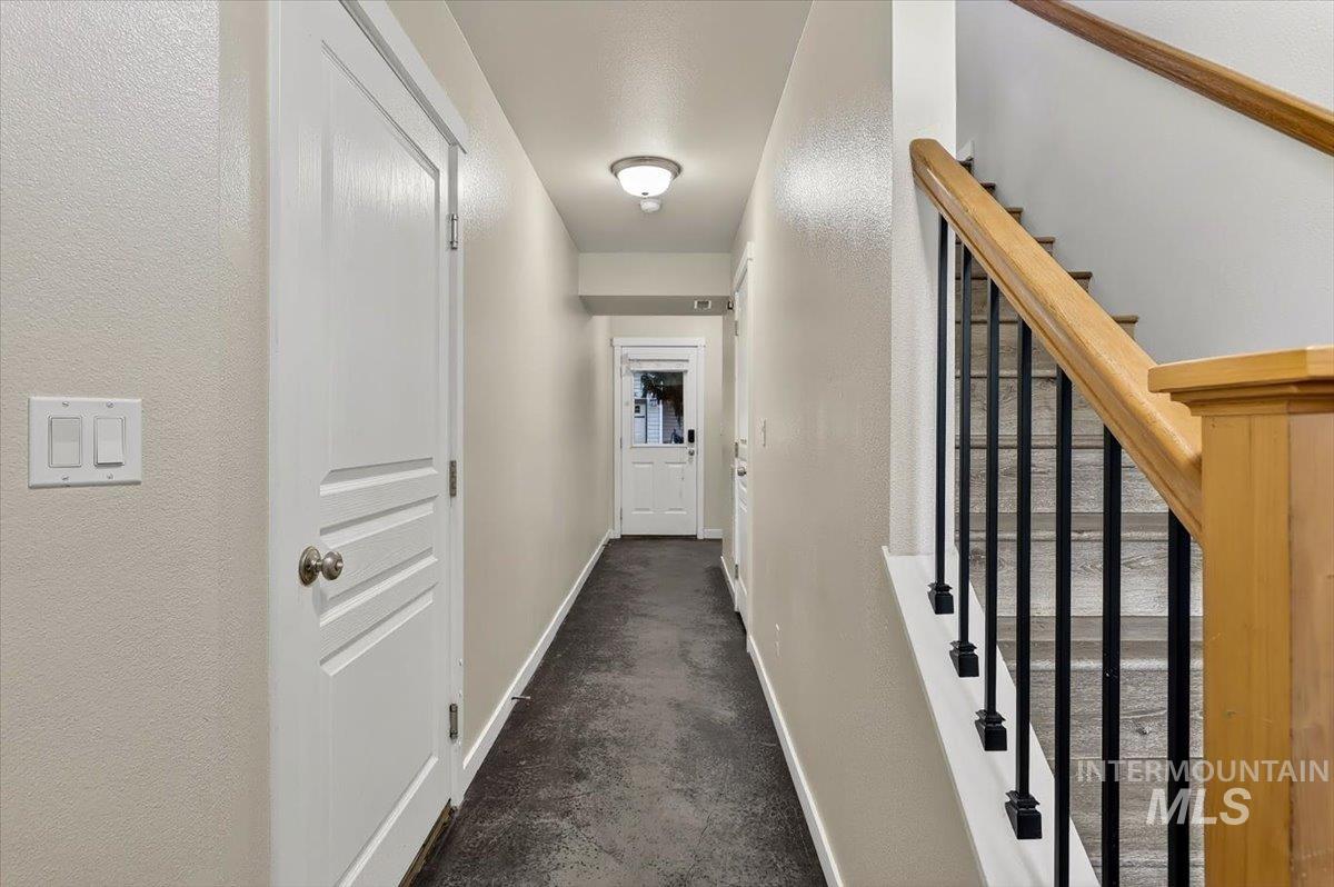 Hallway with light-toned walls, a wood-finish staircase with black metal balusters, and a panel door with brushed nickel hardware