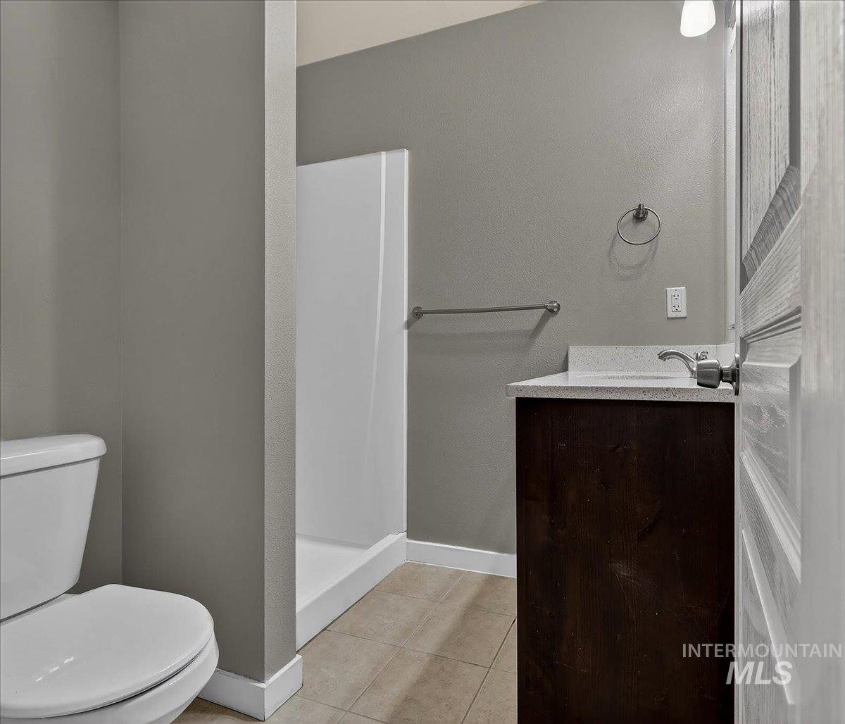 Bathroom featuring a wood-finish vanity with an integrated white sink and light-colored countertop