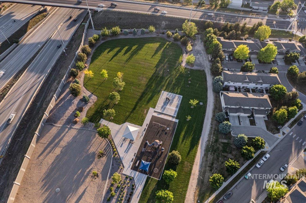Expansive park-like setting featuring a large grassy area, mature trees, and a dedicated playground structure