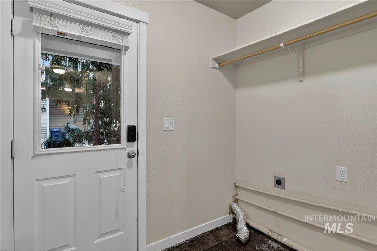 Dedicated laundry area featuring a full-light exterior door, overhead shelving with hanging rod, durable flooring, and appliance hookups