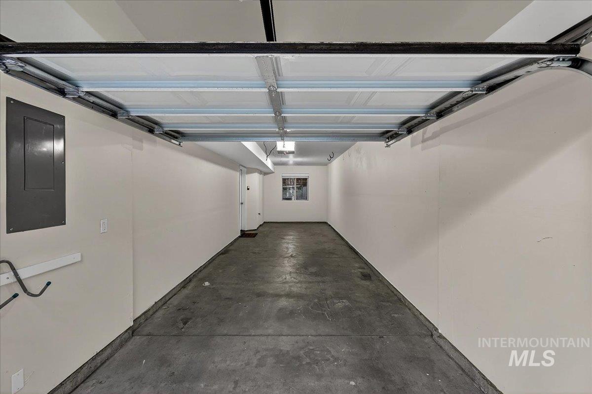 Spacious garage featuring a concrete floor, painted walls, overhead lighting, and an electrical panel