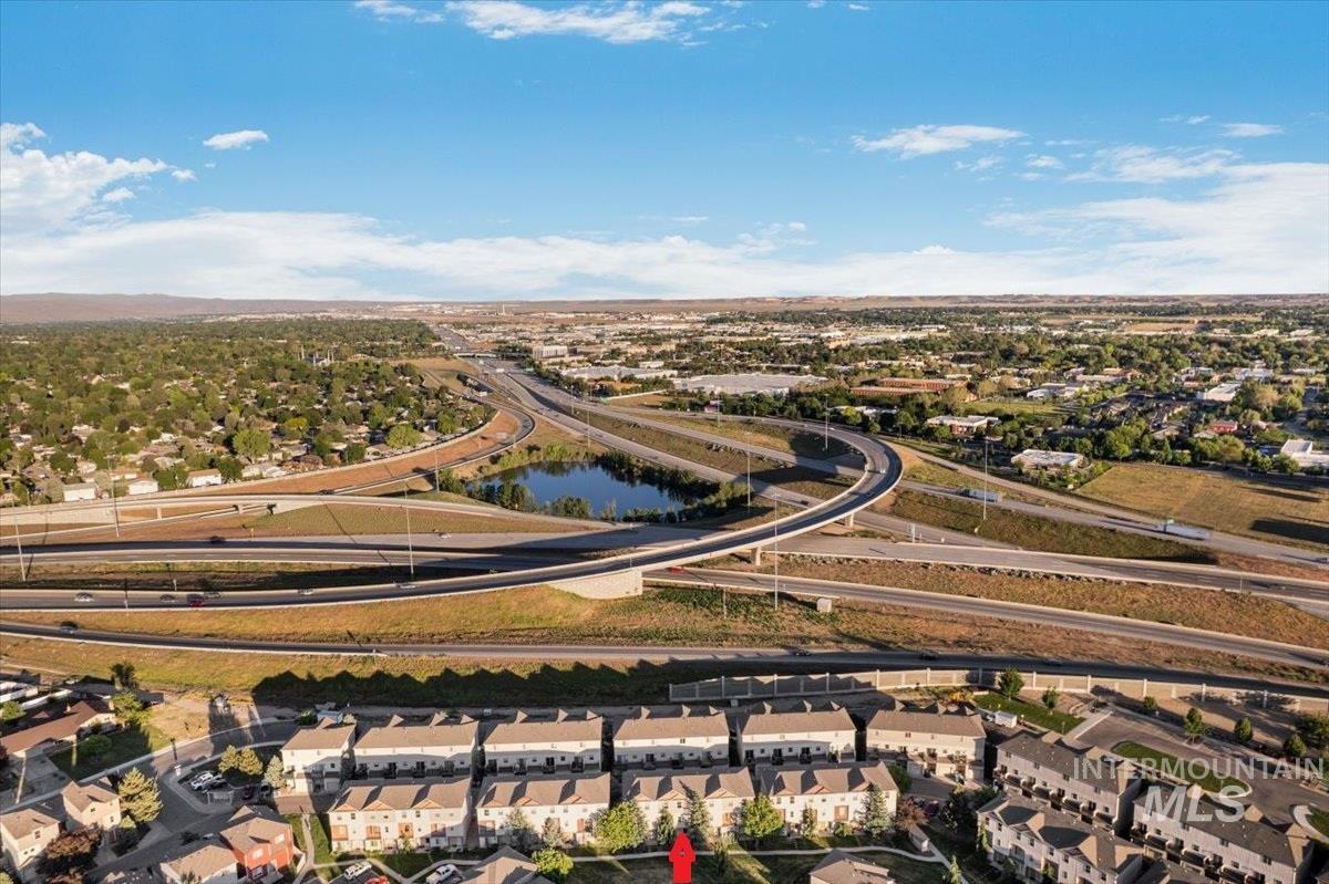 Aerial perspective featuring rows of residential townhomes, extensive highway infrastructure, and a natural water feature