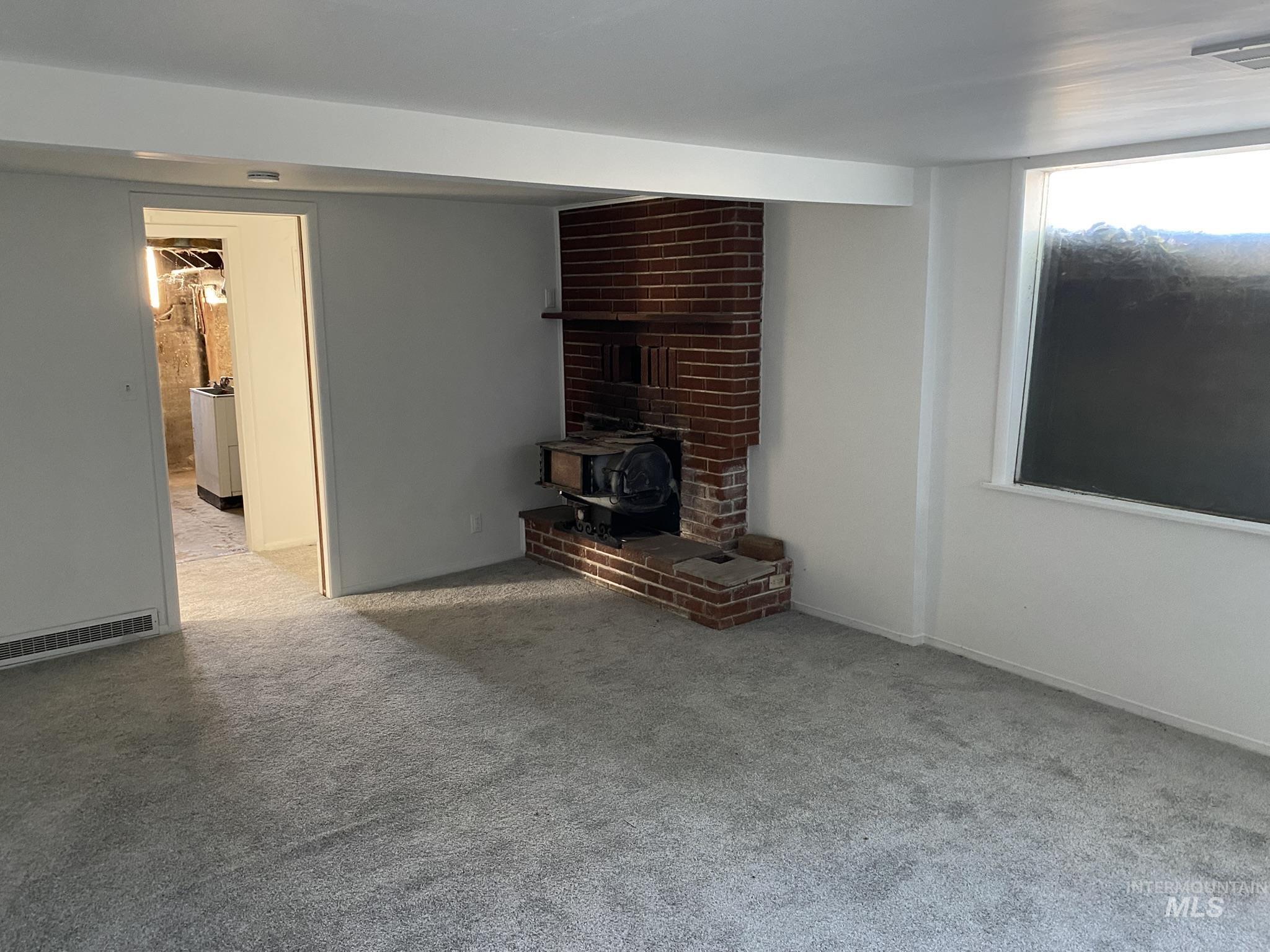 Unfurnished living room featuring a wood stove and light carpet